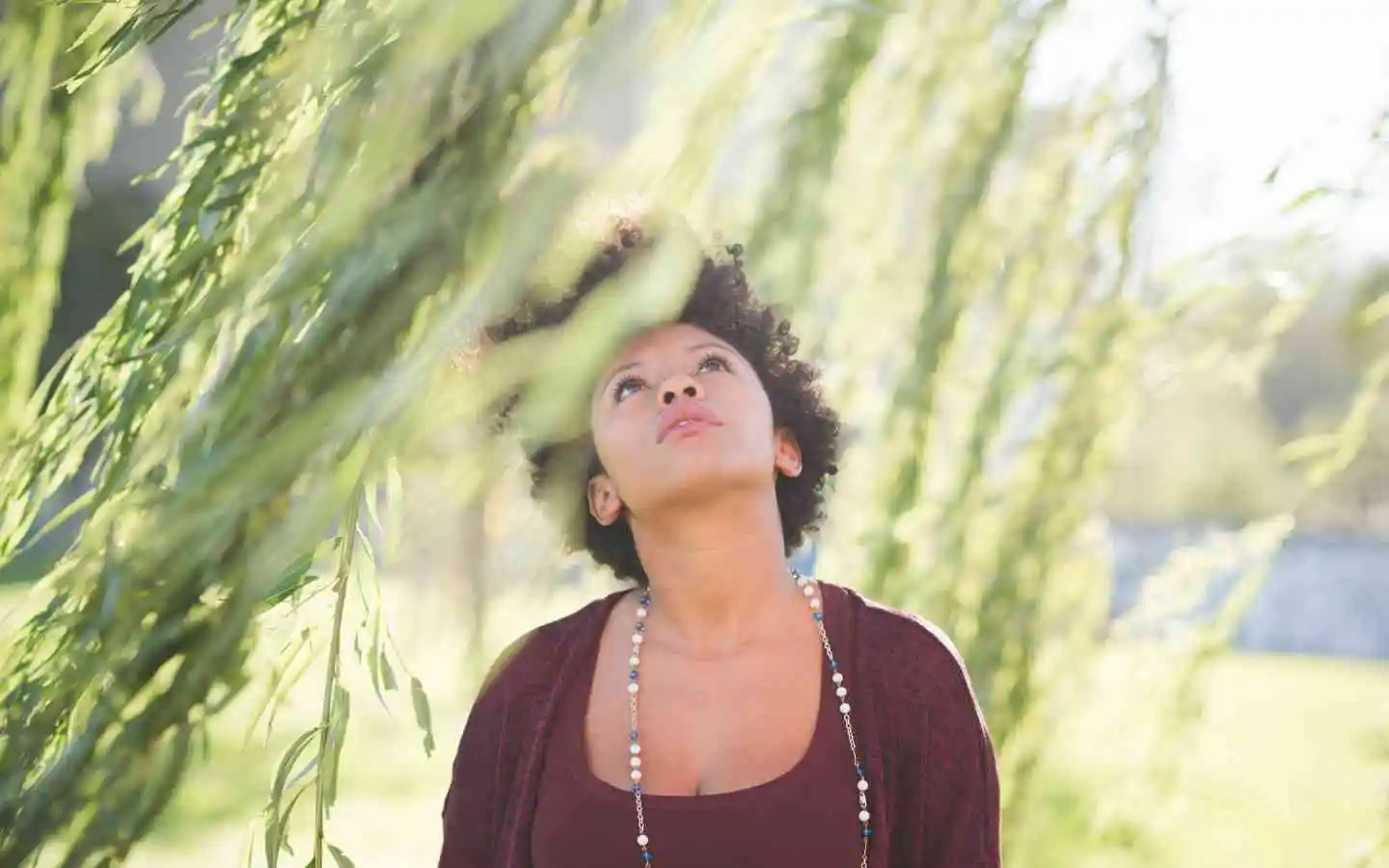 A woman standing in a field of tall grass under a clear blue sky.
