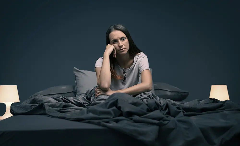 Stressed woman suffering from insomnia, she is sitting in bed and feeling sad
