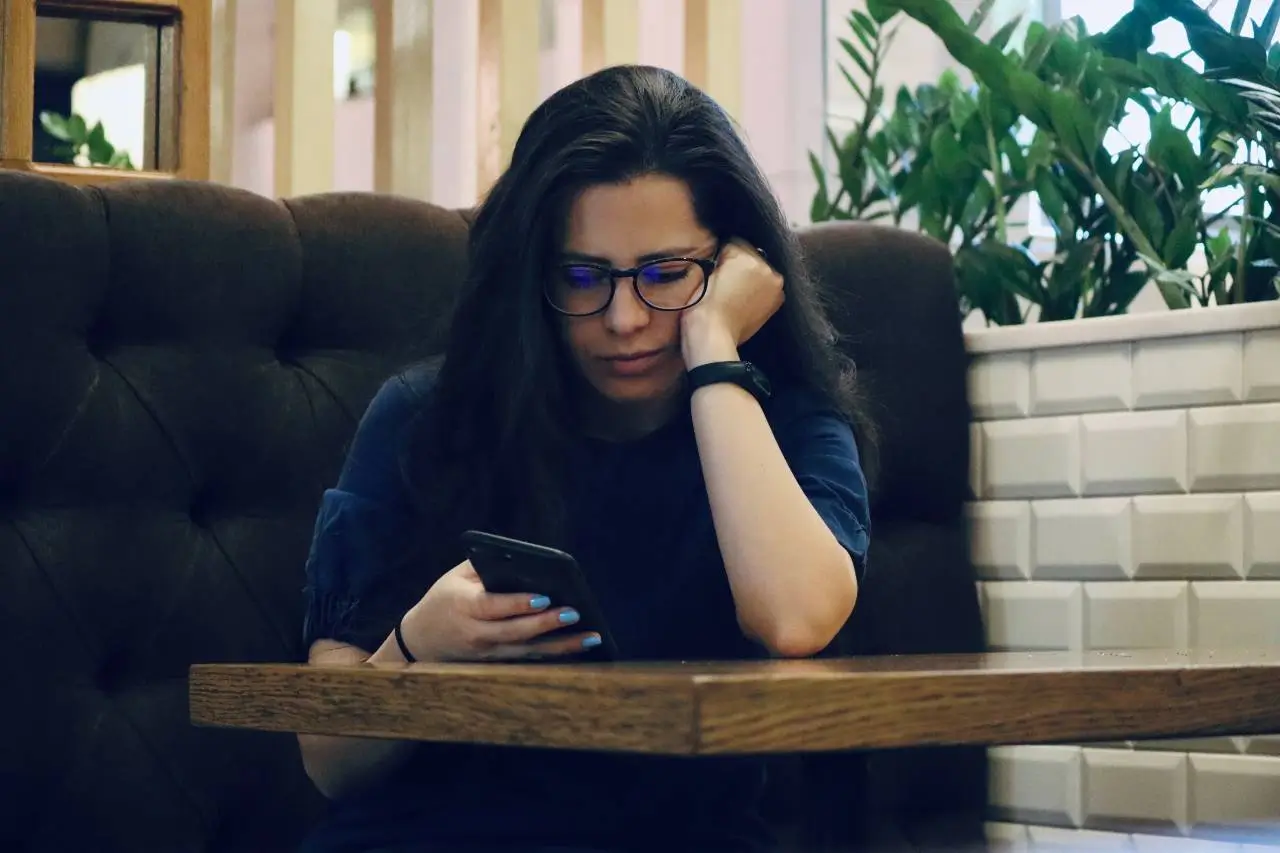 Sad girl looking at her phone