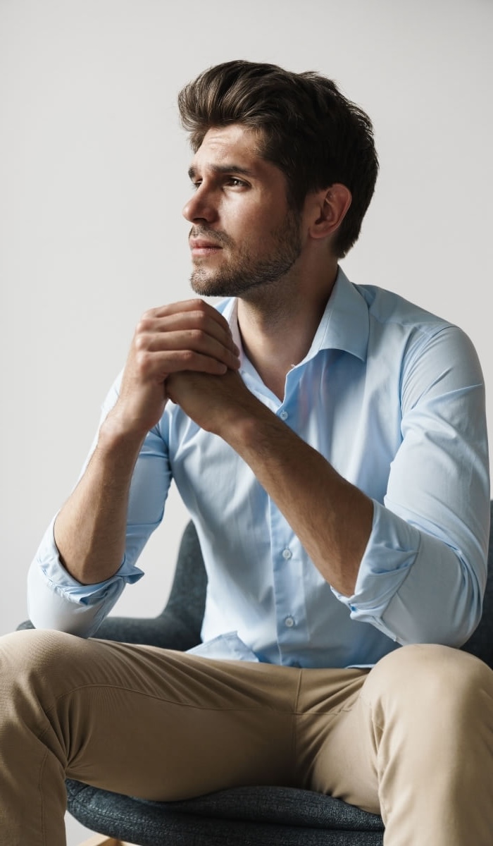A man sits quietly with clasped hands, reflecting on difficult emotions. Image used by Get Reconnected Psychotherapy and Counselling Services. Contact info@getreconnected.ca.