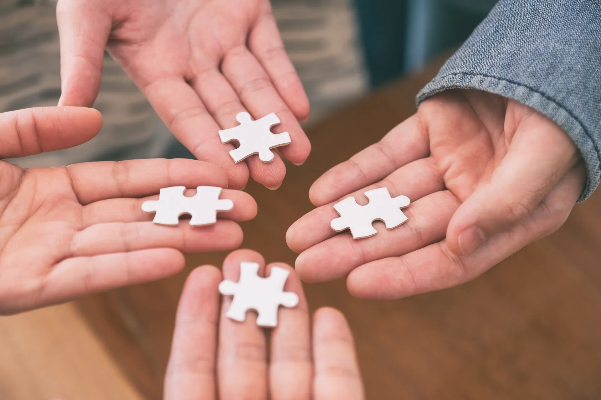 Hands holding white puzzle pieces together