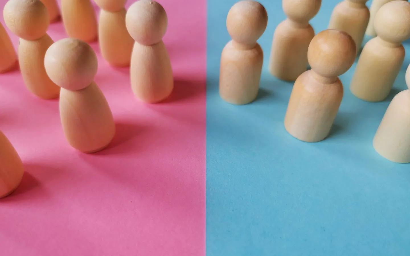 Wooden people on a vibrant blue and pink backdrop.