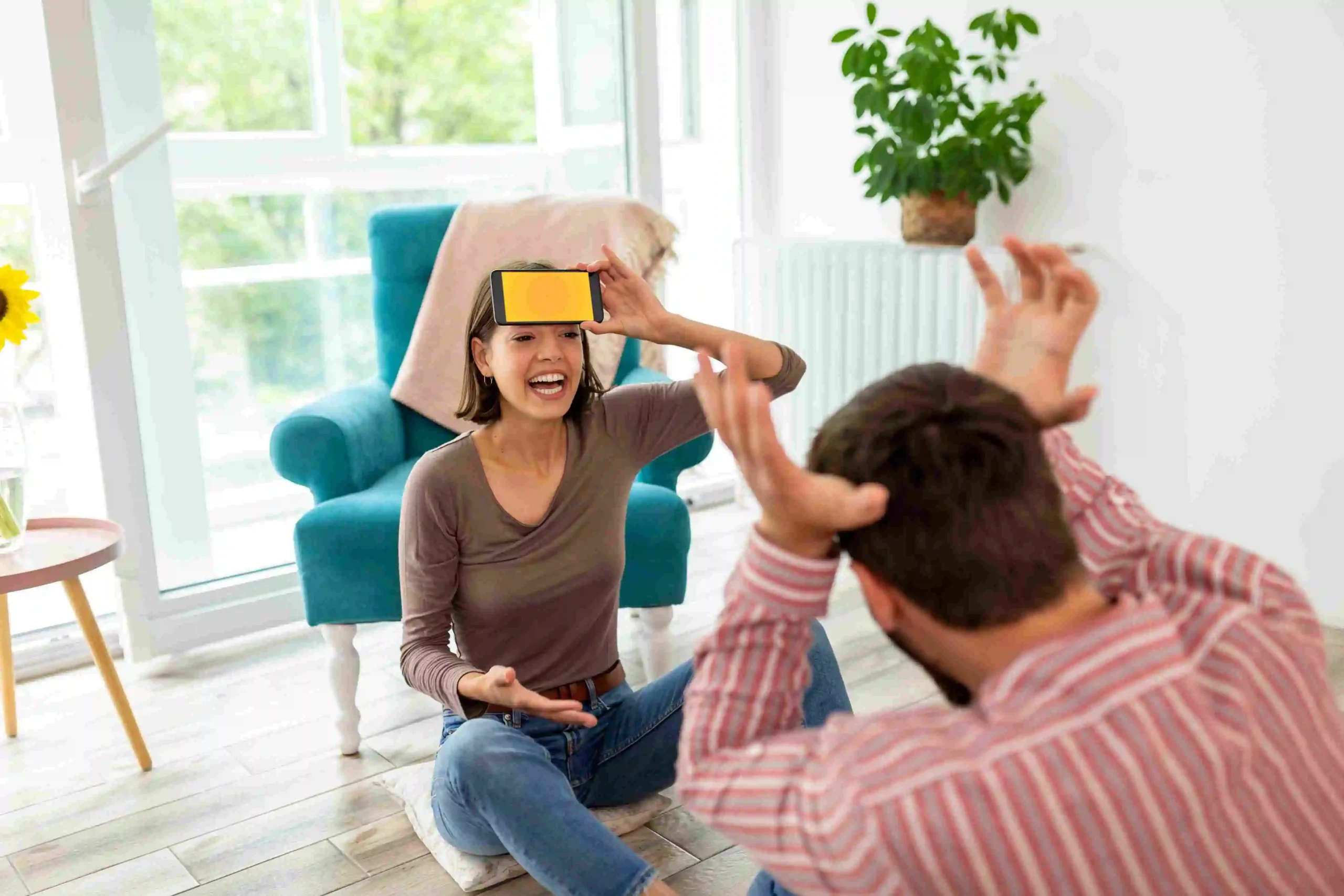 A couple sitting on the floor, immersed in virtual reality with headsets on.