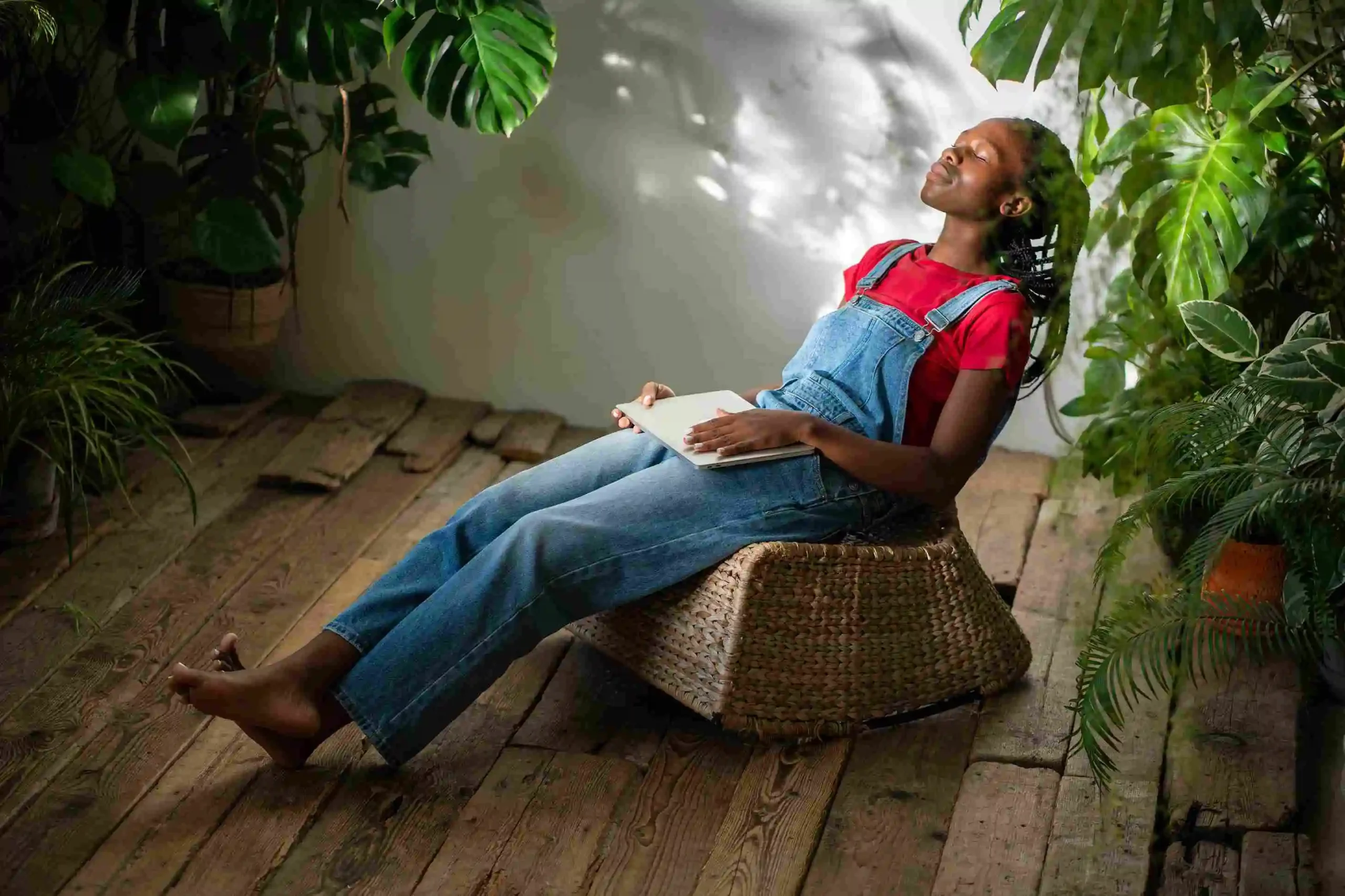  Female relaxing on wicker chair amidst greenery.