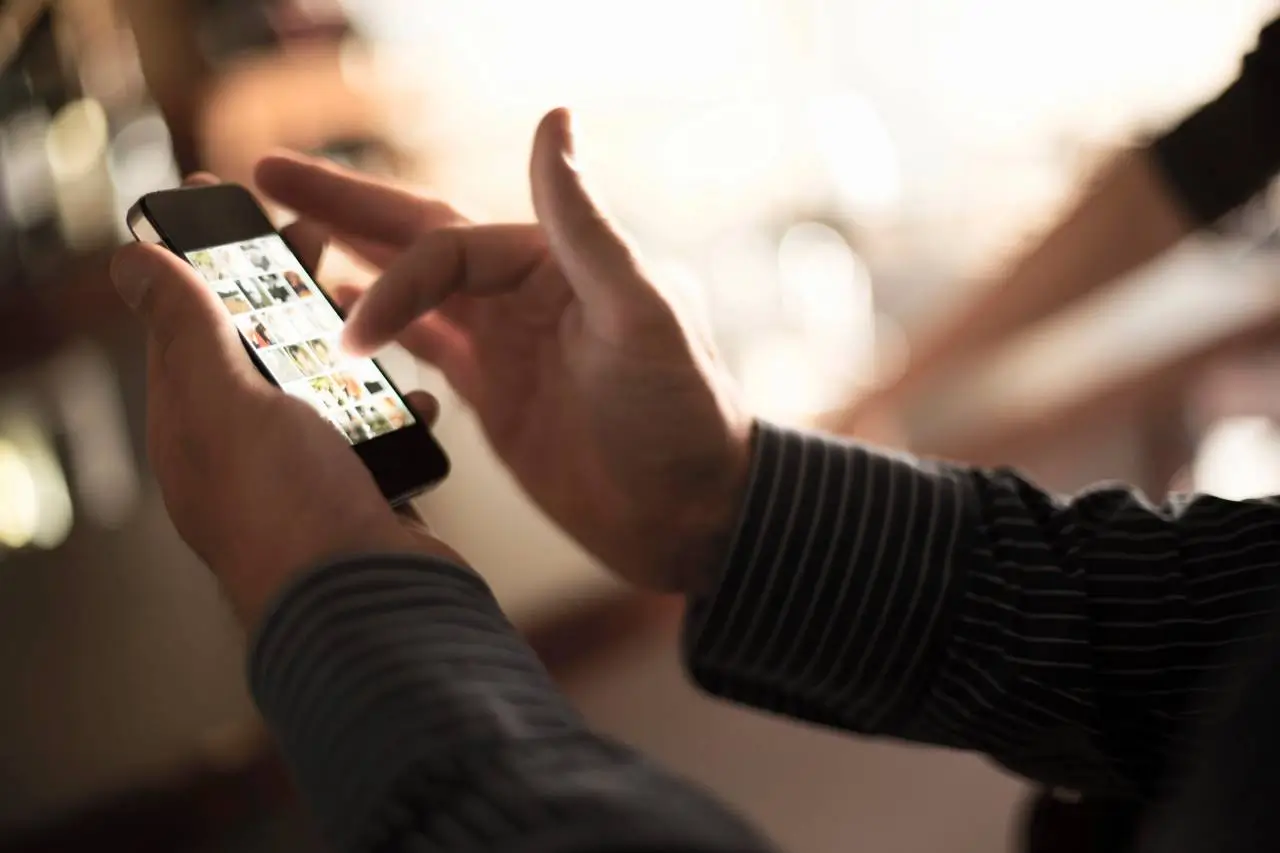 Close up of man using smartphone touchscreen in wine bar